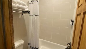 Un baño con inodoro, bañera y cortina de ducha.