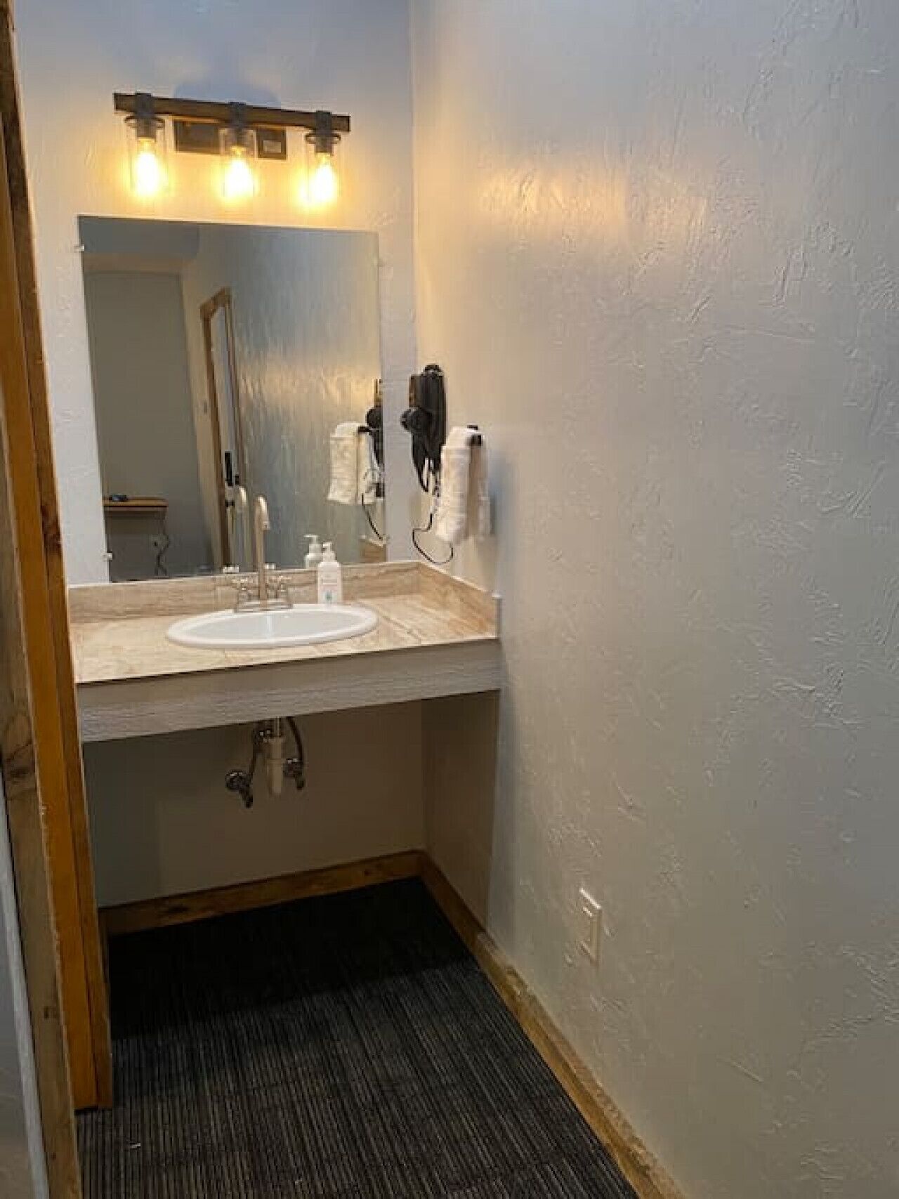 A bathroom with a white sink, a mirror, and a towel dispenser.
