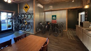 Un intérieur rustique avec des plafonds en bois, un coin repas et des vélos appuyés contre un mur en tôle ondulée.