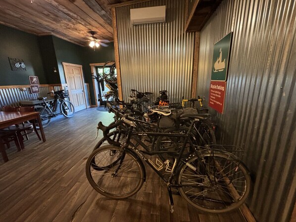 Una habitación con piso de madera, bicicletas, una mesa de comedor y un letrero que indica estacionamiento para bicicletas.