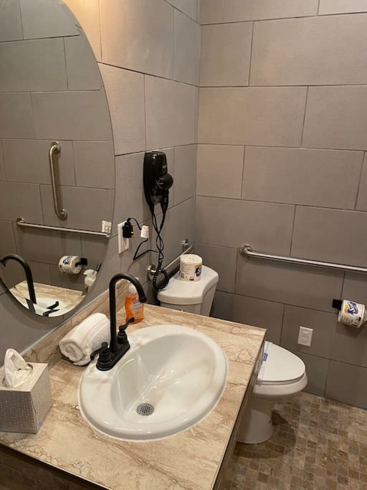 A bathroom with a sink, mirror, toilet, and hand dryer.