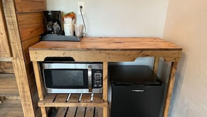 A compact kitchenette with a microwave, a small refrigerator, and a coffee maker on a wooden shelf unit. - Falls Market Inn Riverview, Bike Trail, Fallingwater Hotel, 1 KIng Bed 1 Futon (Ohiopyle)