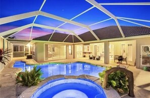 Piscina coberta com vista clara do céu, área de varanda e casa com várias portas e janelas.