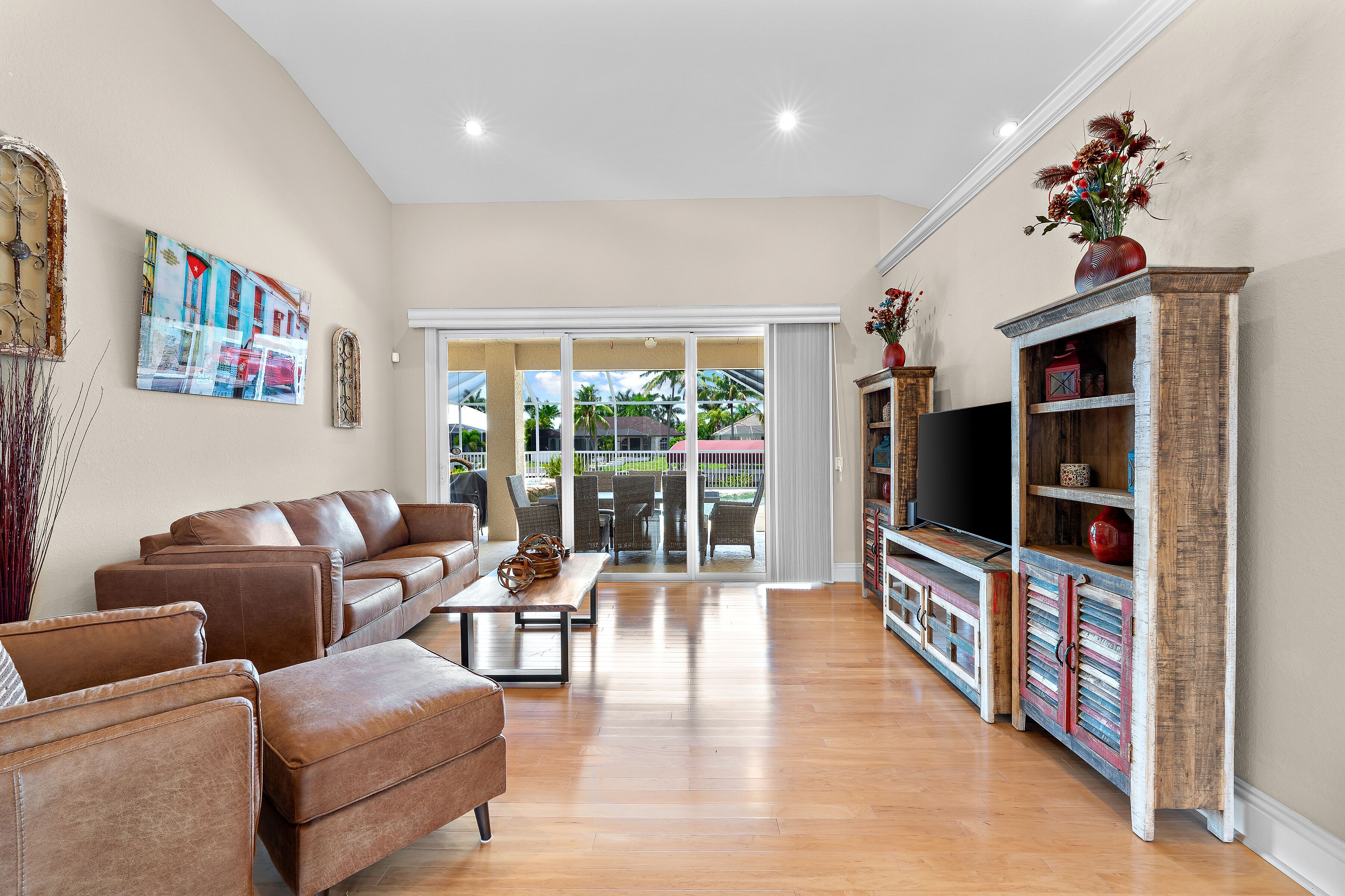 A spacious living room with a brown leather sofa, a coffee table, and a TV on a wooden cabinet.