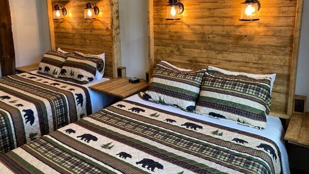 Une chambre avec deux lits, chacun doté d’une tête de lit en bois et d’une literie assortie ornée de motifs d’ours.
