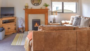 A cozy living room with a fireplace, a television, and a comfortable sofa. - Y Nyth Yn Bwthyn Coed Gellyg (Dinas Dinlle, near Caernarfon)