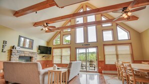 Un salón amplio con chimenea, ventanas grandes y balcón.