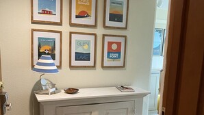 A hallway with a white cabinet, a framed poster of Glen Haven, Lake Michigan, and other local attractions.