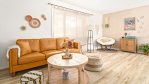 Un saló modern amb un sofà de cuir, una taula de centre rodona de fusta i un butac armchair blanc.
