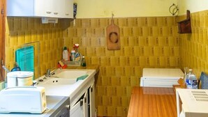 A compact kitchen with wooden cabinets, a sink, a countertop with a toaster, and a wooden dining table.