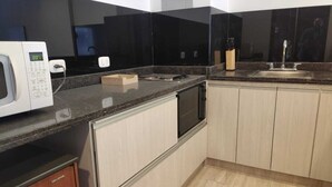 Een moderne keuken met een magnetron, fornuis, spoelbak en houten kastjes.
