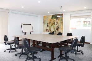 A conference room with a large table, six chairs, a whiteboard, and a painting on the wall.