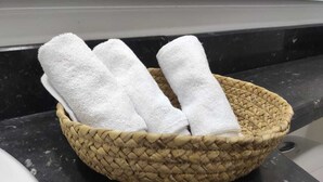 Een gevlochten mand met drie witte handdoeken op een donker aanrecht.