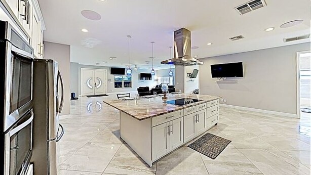 A modern kitchen with a central island, stainless steel appliances, and recessed lighting.
