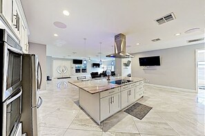 A modern kitchen with a central island, stainless steel appliances, and recessed lighting. - Spacious Home with Pool East Lantana (Lantana)