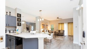 A modern kitchen with a central island, built-in appliances, and a dining area with a sofa and coffee table.