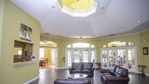A spacious lobby with leather sofas, a coffee table, and a large glass door leading to a fitness area.
