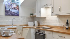 A kitchen with white cabinets, a Bosch oven, a toaster, and a wine bottle. - The Stables at Early Autumn (Sevenoaks)