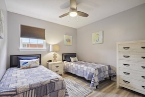 A bedroom with two beds, a nightstand with a lamp, a dresser, and a ceiling fan. - Beach Bungalow! Minutes to the Beach, Shopping, & Downtown! (Long Beach)
