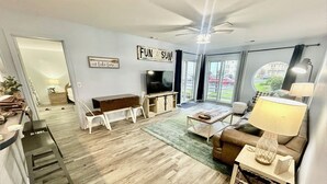 A living room with a TV, sofa, and a dining area with chairs and a table.