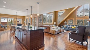 Amplia sala de estar con piso de madera, una isla central con pileta y un área de descanso con sofá y sillones.