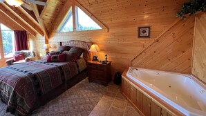 A bedroom with a bed, a nightstand, a lamp, a window, and a bathtub. - Beautiful Cabin to Rest & Relax, 1 Mi to Parkway, Hot Tub/Fireplace/Pool/Jacuzzi (Pigeon Forge)