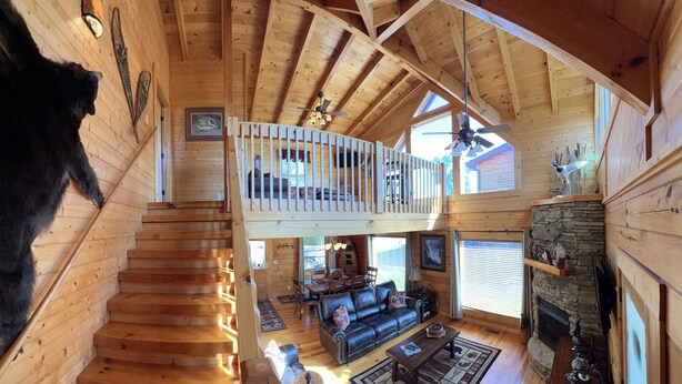 A wooden cabin with a loft bedroom, a fireplace, and a dining area. - Beautiful Cabin to Rest & Relax, 1 Mi to Parkway, Hot Tub/Fireplace/Pool/Jacuzzi (Pigeon Forge)