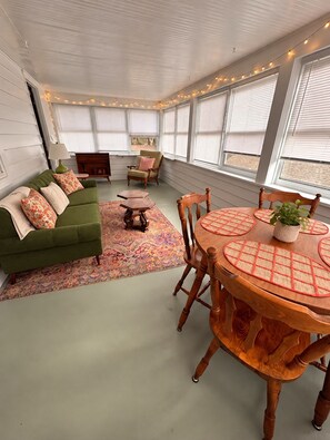 A room with a green sofa, a wooden dining table with placemats, and a patterned rug. - Comfy Flat with Old World Charm in the city (Jackson)