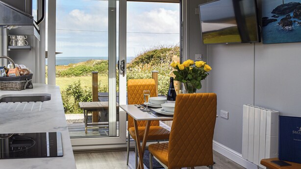 Una cocina moderna con zona de comedor, un televisor montado en la pared y vistas al mar.