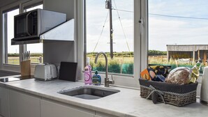 Una cocina equipada con microondas, tostadora y lavabo. Hay cestas con pan y una botella de detergente.