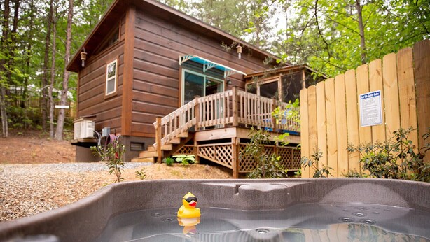Una cabaña de madera con jacuzzi y un patito de goma.