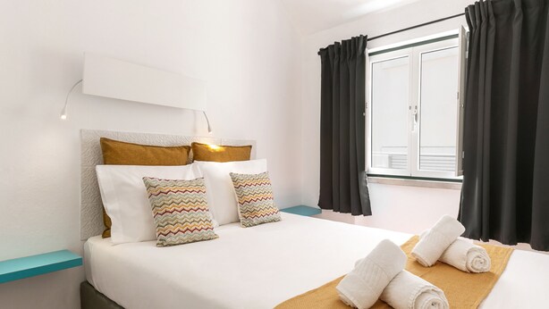 A neatly made bed with white linens, a brown throw blanket, and rolled towels. - Casa Casulo - 2min walking to the Beach (Nazaré)