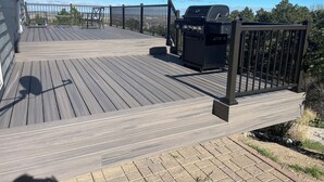 Une terrasse en bois avec un barbecue et une rambarde en métal.