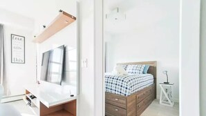 Ein modernes Schlafzimmer mit Bett, Nachttisch und einem Wand-Fernseher.