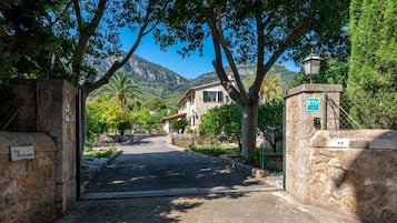 Un portón de piedra que da a una casa con montañas al fondo.