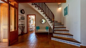 A staircase with wooden railings and blue-tiled steps, leading to a landing with a white bench and a clock on the wall. - Sa Finqueta Luxury Elegant Mansion with breathtaking views in Sóller (Sóller)