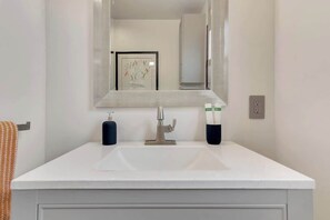 A bathroom with a white sink, a mirror, and two soap dispensers. - MaRVELOUS MiDCENTURY-Hot Tub, 5 Blocks to Downtown (Paso Robles)