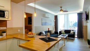 A modern apartment with a kitchen, dining area, and living room. It features a wooden kitchen island, a dining table with chairs, a sofa, and a ceiling fan. - Stylish Friendly Holiday Home (Playa del Inglés)