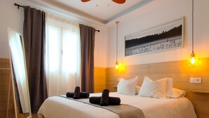A hotel room with a large bed, two bedside lamps, a painting on the wall, and a window with curtains. - Stylish Friendly Holiday Home (Playa del Inglés)
