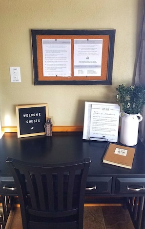 A desk with a corkboard displaying notices, a welcome sign, a guest book, and a potted plant. - Lazy Bear Lodge with Boat Slip on Lake Tomahawk/Minocqua Chain (Lake Tomahawk)