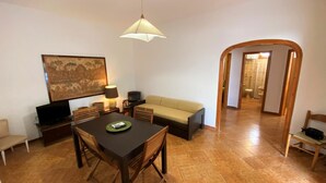 Una habitación con una mesa de comedor, sillas, un sofá, un televisor y una lámpara.
