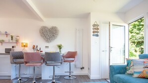 Eine moderne Küche mit Barhocker, einer herzförmigen Wanddekoration und einem Essbereich mit Tisch und Stühlen.