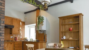 A kitchen with wooden cabinets, a dining table with chairs, and a hanging plant.