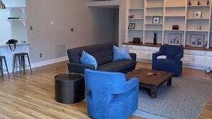 A modern living room with a sofa, armchairs, a coffee table, and a bookshelf. - Beautiful and spacious loft in the Heart of Atlanta! (Atlanta)