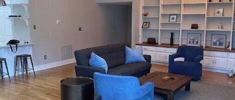 Uma sala de estar moderna com sofá, poltronas, mesa de centro e estante.