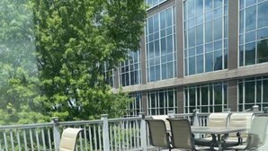 An outdoor deck with a table and chairs, a white railing, and a building with large windows in the background. - Beautiful and spacious loft in the Heart of Atlanta! (Atlanta)
