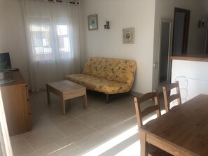 Ein Wohnzimmer mit einer Couch, einem kleinen Tisch und einem Holzesstisch.