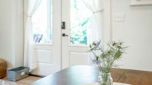 A room with a wooden table, a vase with flowers, and a door with curtains.