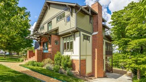 A two-story house with a brick facade, a green roof, and a covered porch.