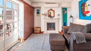 A living room with a fireplace, a sofa, a coffee table, and a large window with blinds.